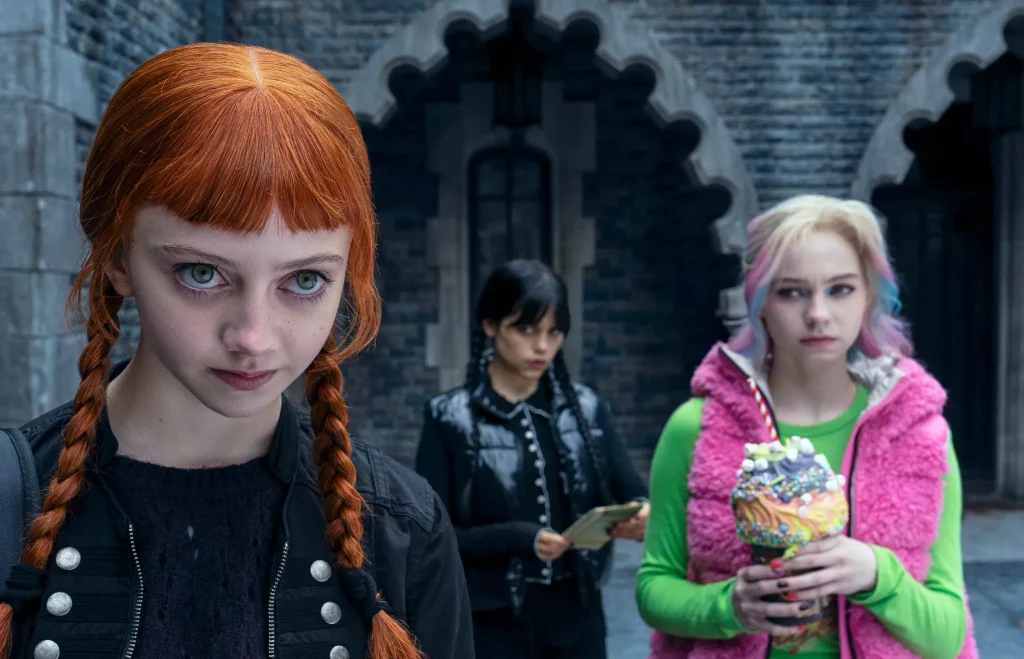 Wednesday Season 2 highlights three actresses discussing gothic identity, set against a dark, atmospheric backdrop.