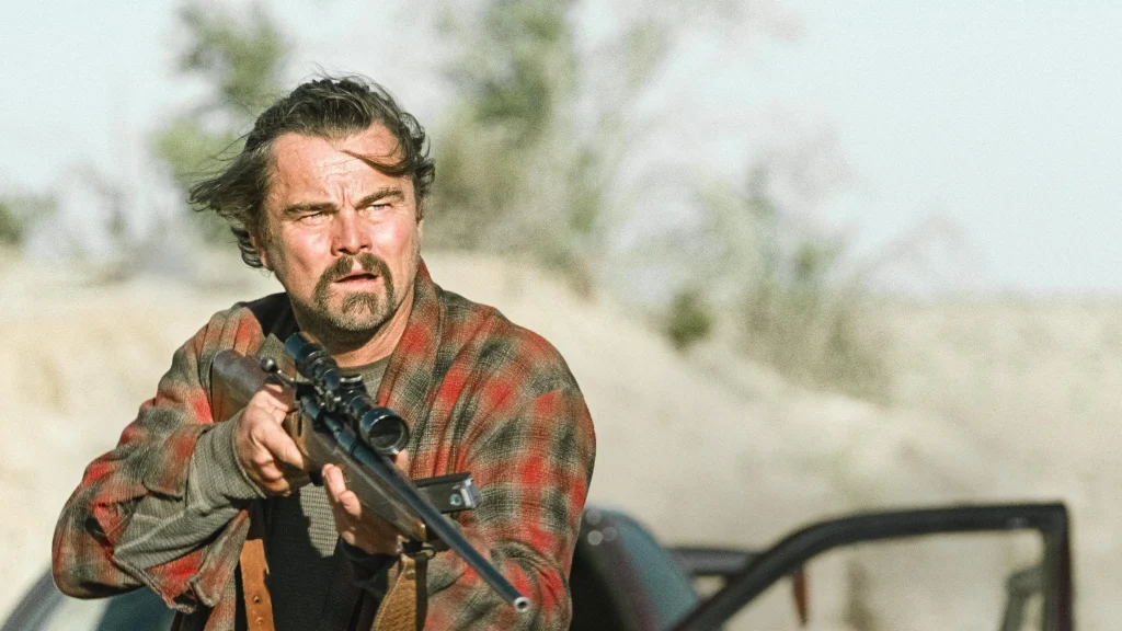 A man prepares to fire his gun, his expression fierce, amidst a visually captivating but tumultuous war scene.