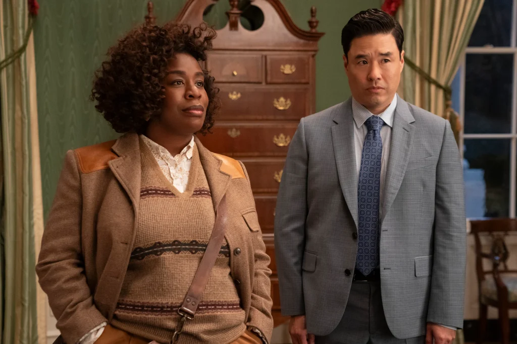 At a crime scene from "The Residence," a black female police officer stands next to an Asian man, both observing the area.