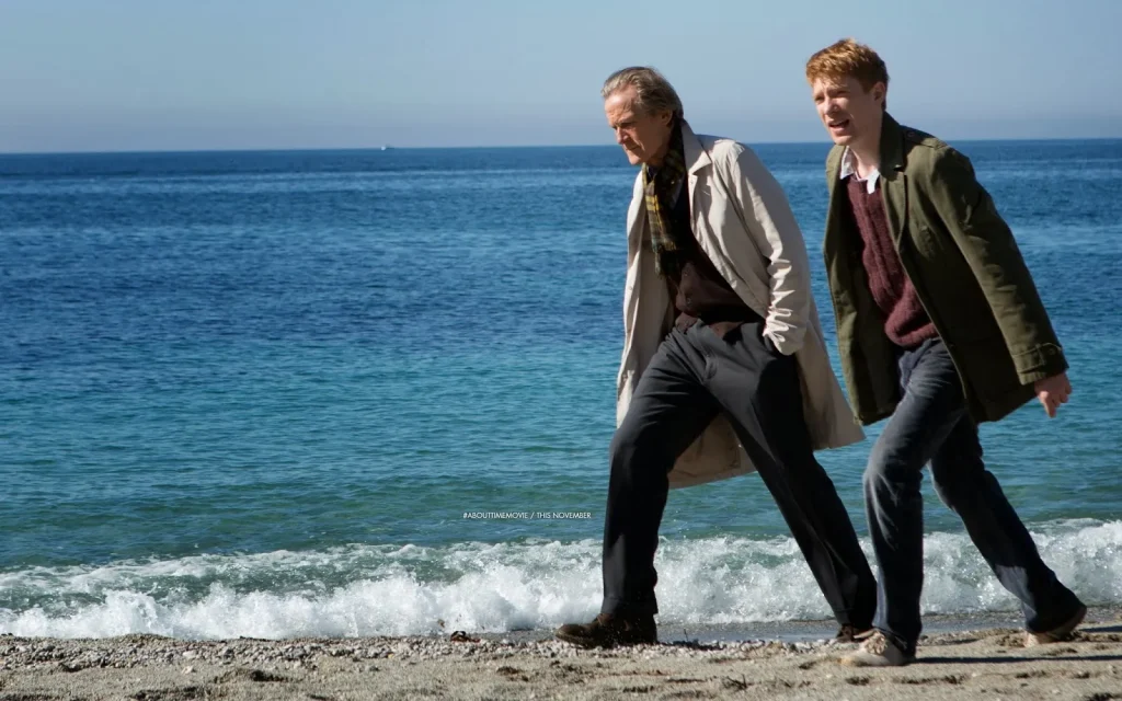 A man and his grandfather stroll along the coast, engaged in a heartfelt conversation about time travel and memories.