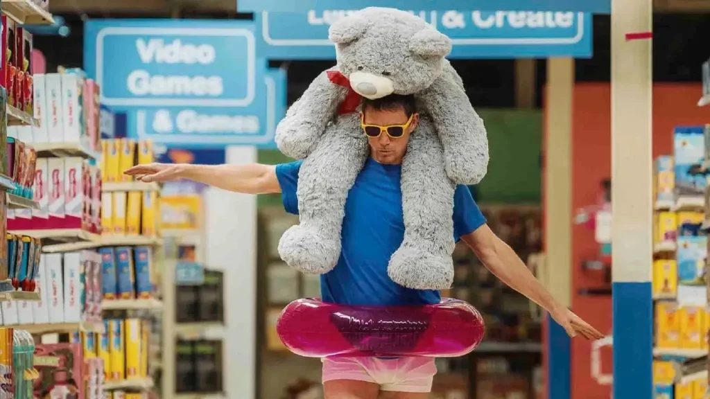A man holding a gun, a toy bear, and a swimming circle, walking on the street.