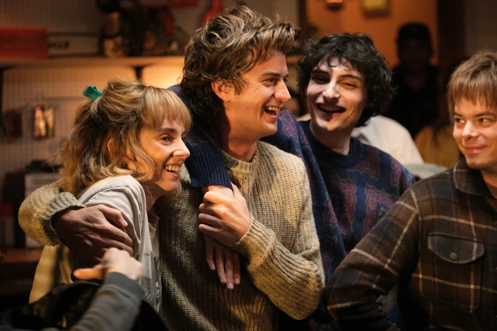 A group of characters from Stranger Things Season 5 share smiles, celebrating their emotional farewell to Hawkins and each other.