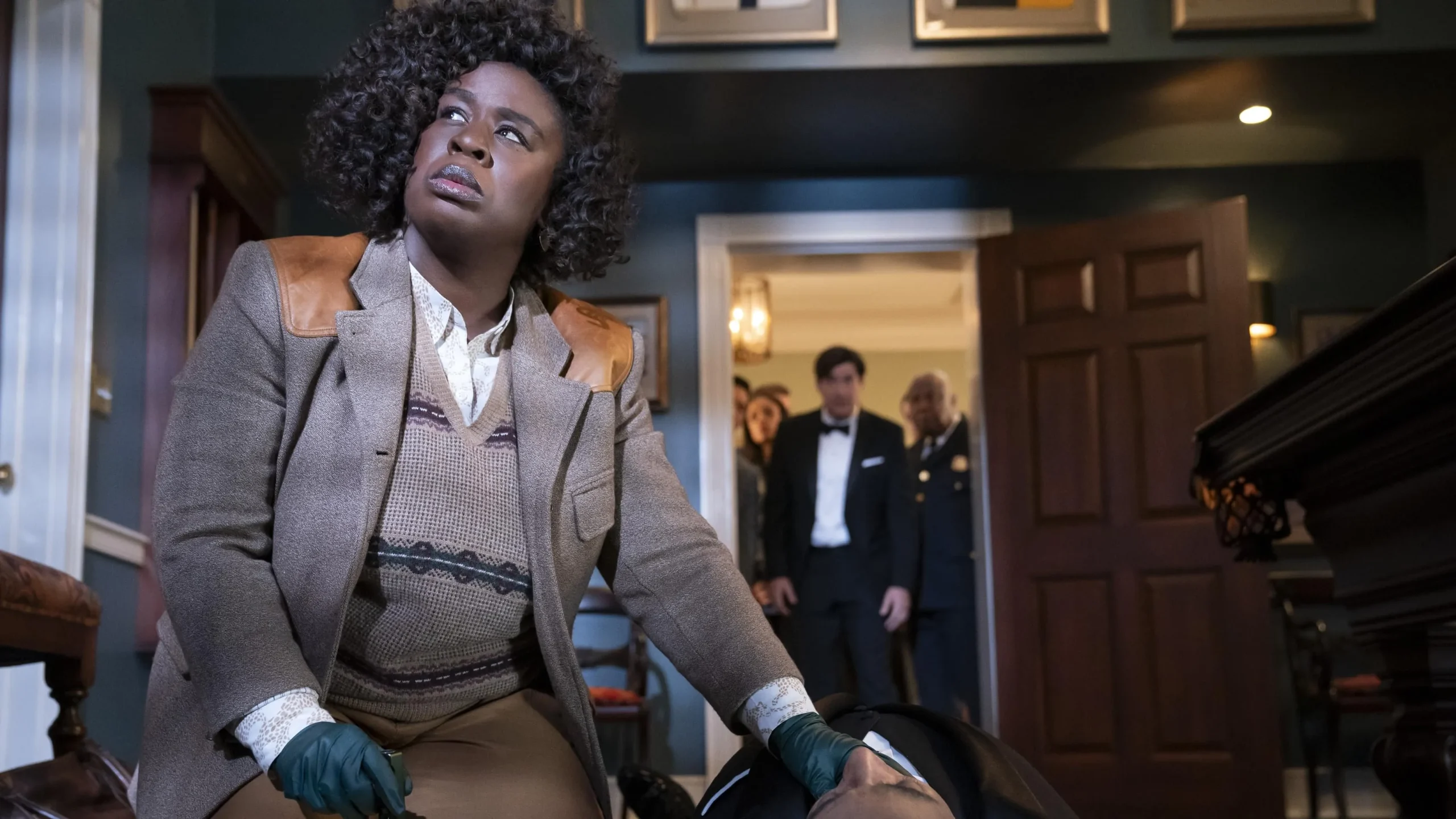 A black female police officer gazes thoughtfully out the window at a crowd behind a crime scene in the TV series "The Residence."