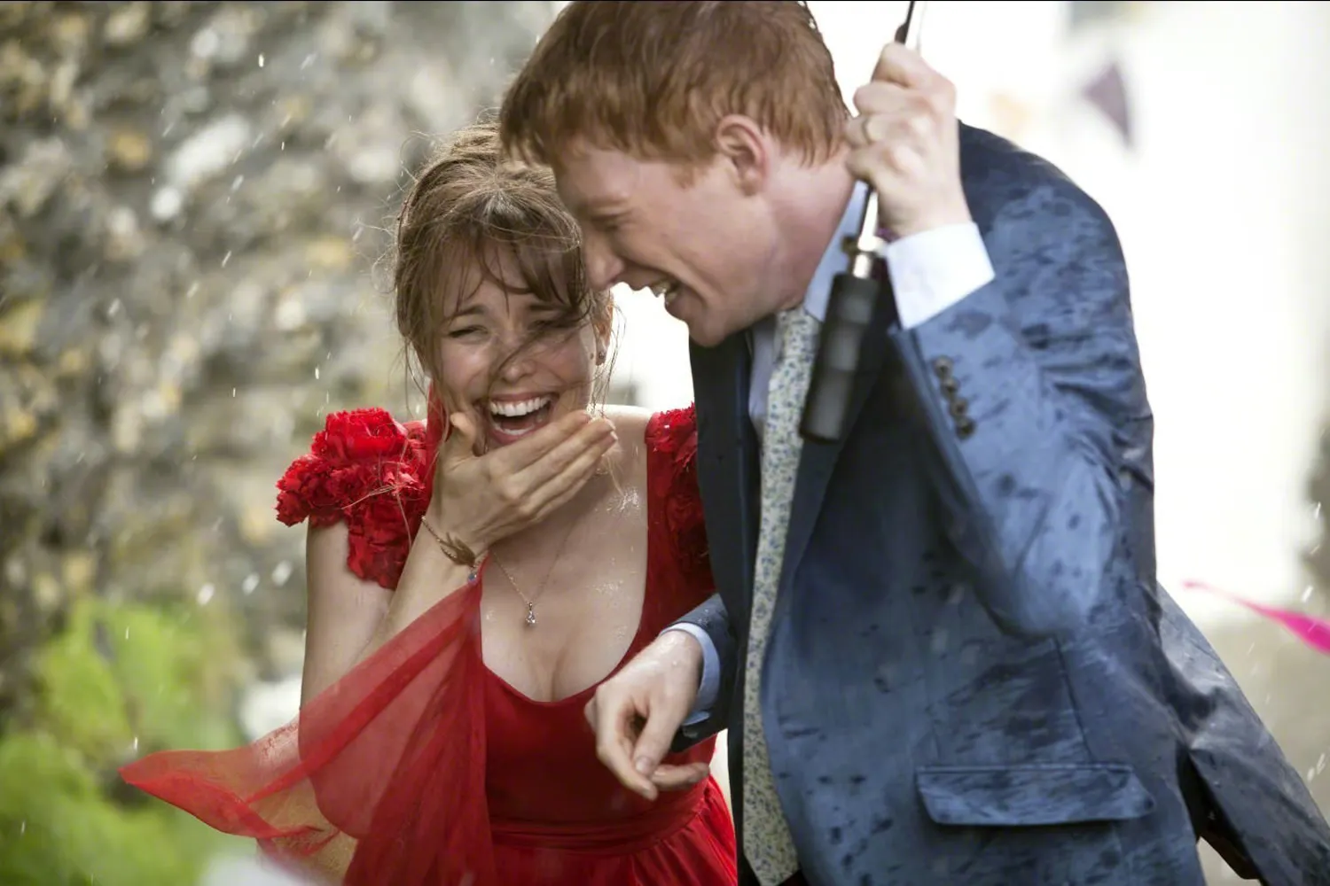 In the rain, a man and his girlfriend embrace, embodying the charm of time travel in the film "About Time."